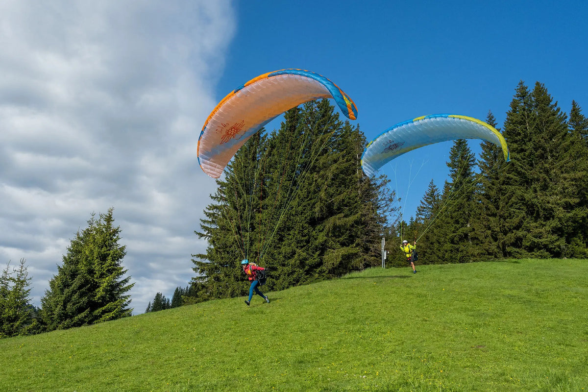 Icaro Pica 2 Gleitschirm bei Paragliding, Menschen beim Schirmfliegen auf Hügel, betont Sicherheit und Stabilität für Schulung und freies Fliegen.
