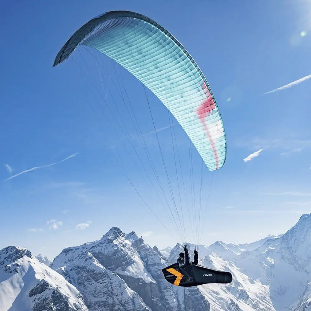 Niviuk Arrow P 2 – Ultraleicht Liegegurtzeug über verschneiten Bergen; Pilot im aerodynamischen Gurtzeug, perfekt für lange, komfortable Gleitschirmflüge.