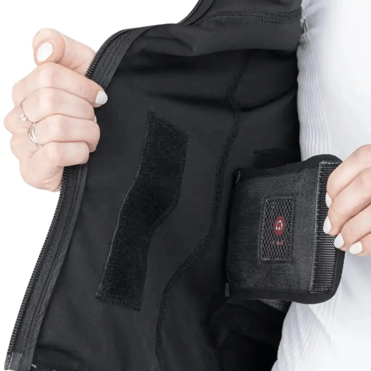 Schwarze, beheizbare Weste mit Klettverschlüssen und integrierter Tasche für ein Heizmodul, ideal für Outdoor-Aktivitäten.