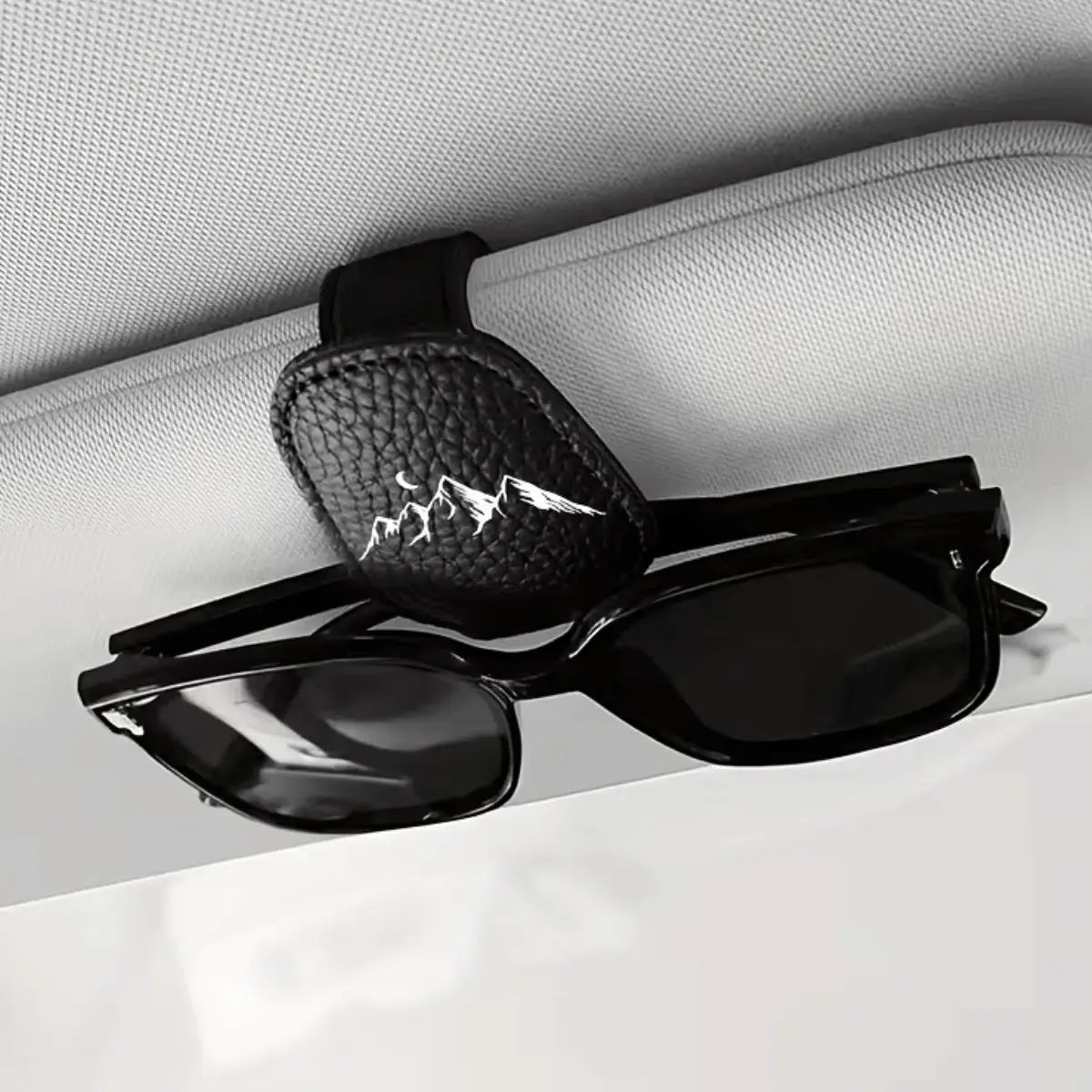 Schwarzer Leder-Brillenhalter für das Auto mit Bergsilhouette, der eine Sonnenbrille sicher an der Sonnenblende befestigt.