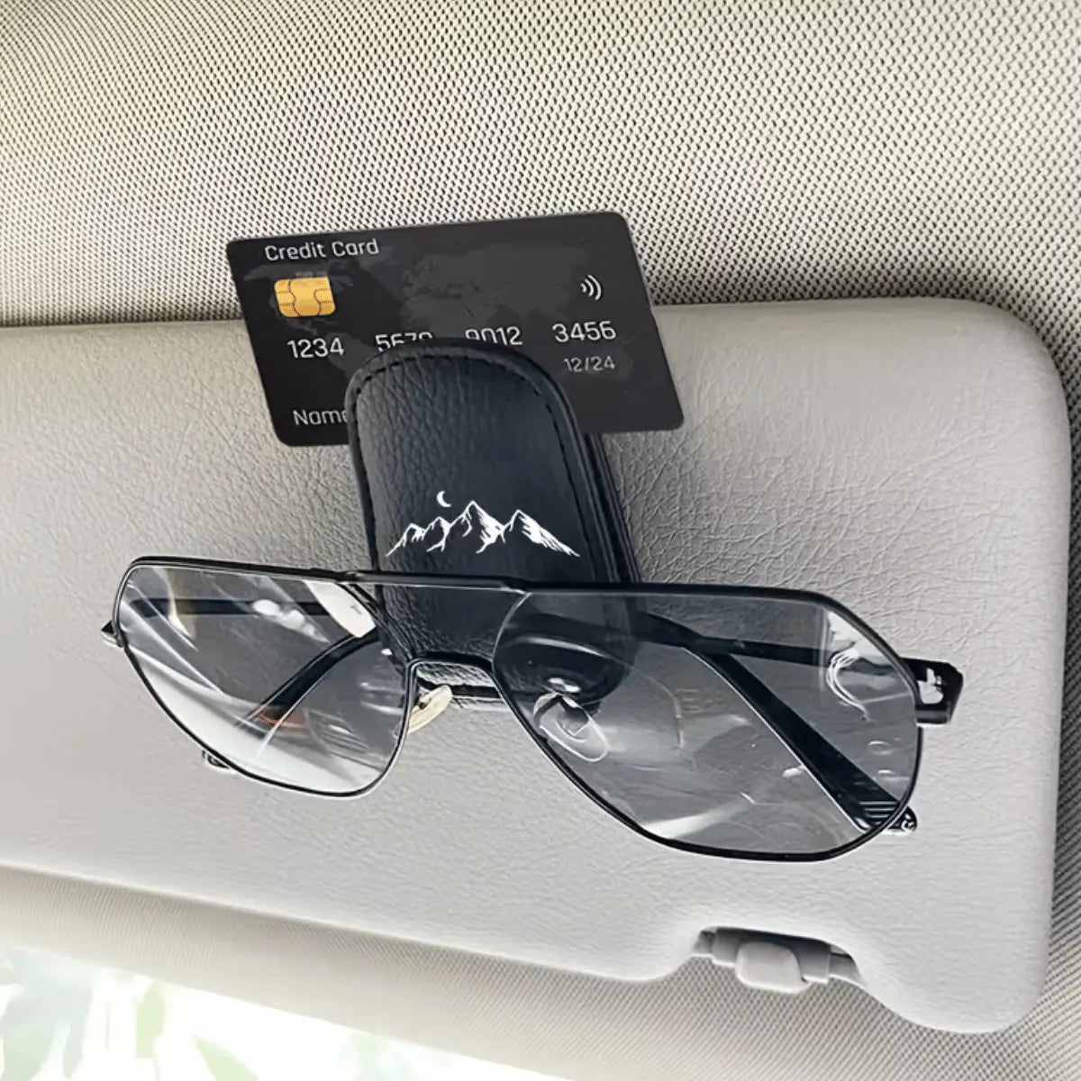 Schwarzer Leder-Brillenhalter für das Auto mit Bergsilhouette, der eine Sonnenbrille sicher an der Sonnenblende befestigt.