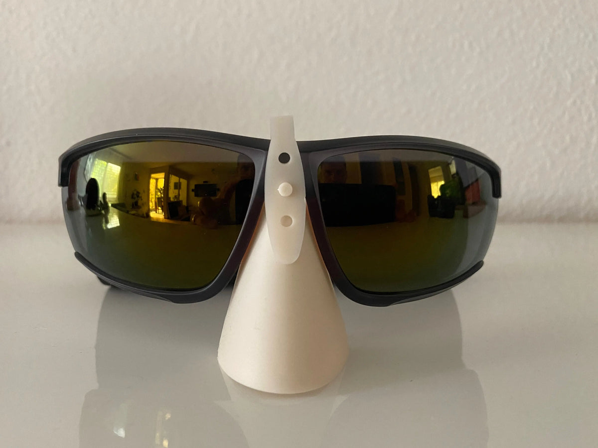 Nasen Sonnenschutz für Sonnenbrillen auf weißem Ständer, bietet effektiven Schutz vor Sonnenschäden, sehr hautfreundlich und individuell anpassbar für verschiedene Brillengrößen.