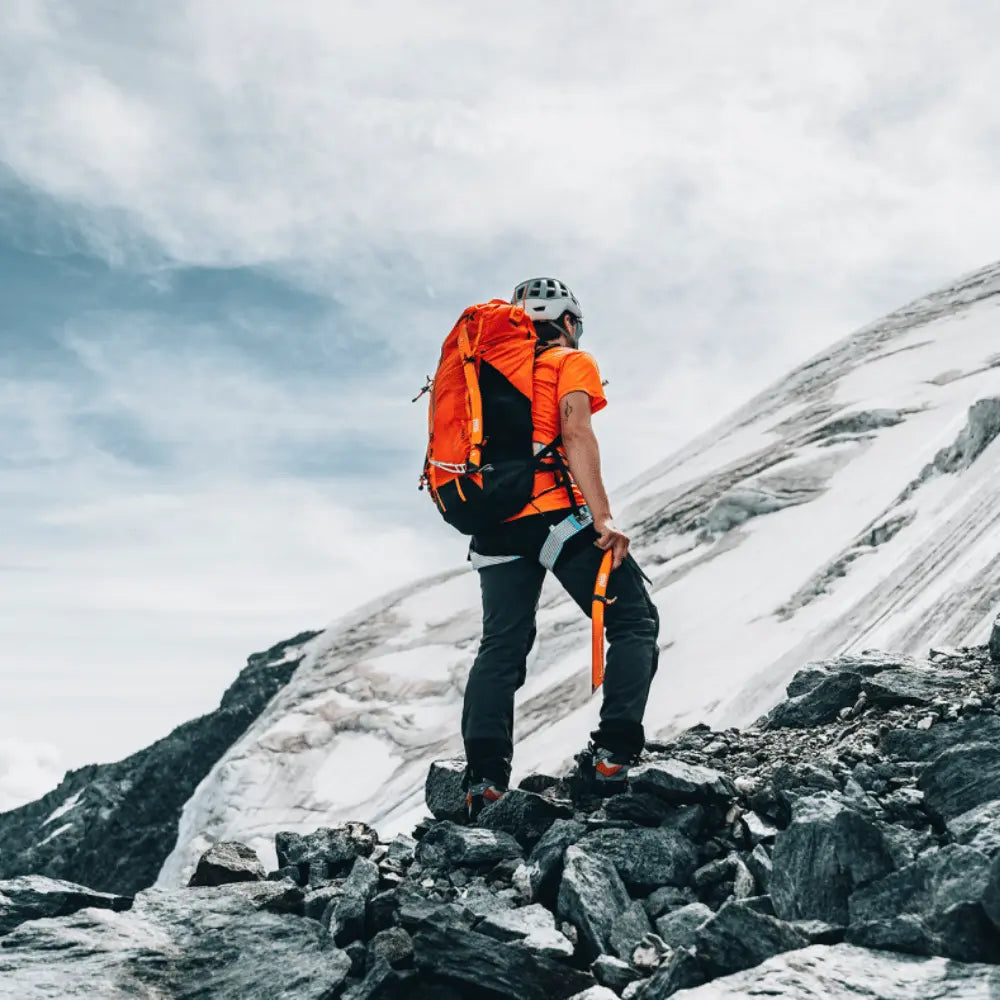 Mann mit Niviuk Expe 45 Rucksack beim Bergsteigen im Winter, ergonomisch für maximalen Komfort, ideal für Gleitschirmausflüge und kurze Wanderungen.