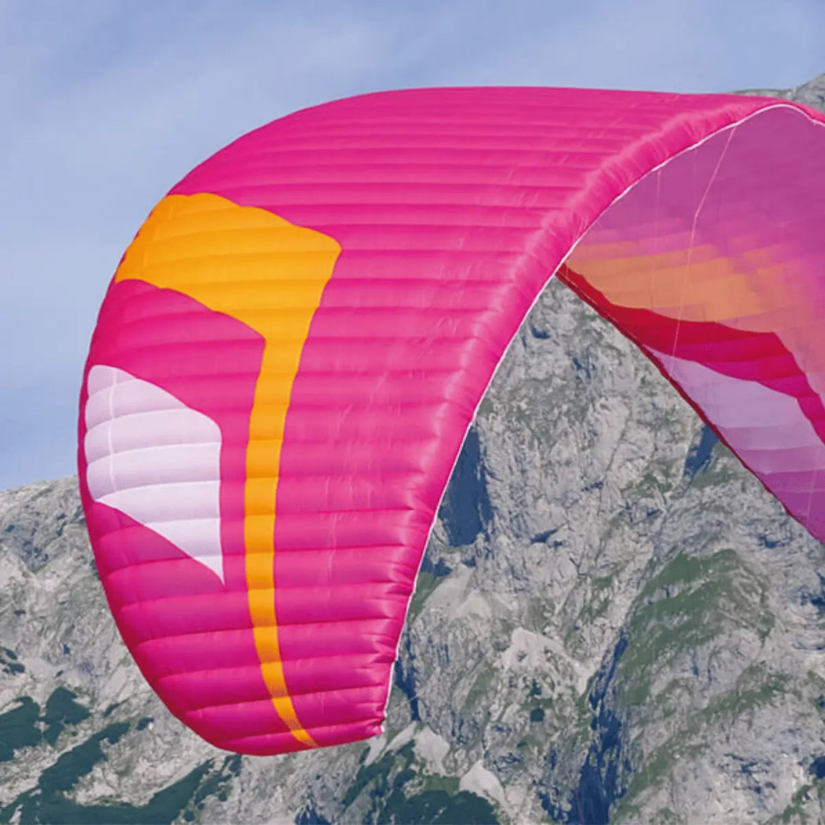 Leichter, mittelgroßer Niviuk Hiko P Gleitschirm in Pink mit orangefarbenen und weißen Akzenten, bereit zum Fliegen vor einer Bergkulisse.