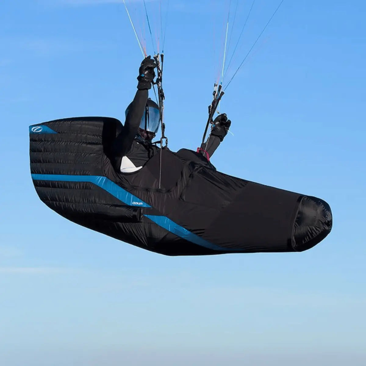 Ozone Ozium 3 Pod Gurtzeug, ein schwarzer Gleitschirm-Sitz mit blauen Akzenten, der einen Piloten in der Luft zeigt.