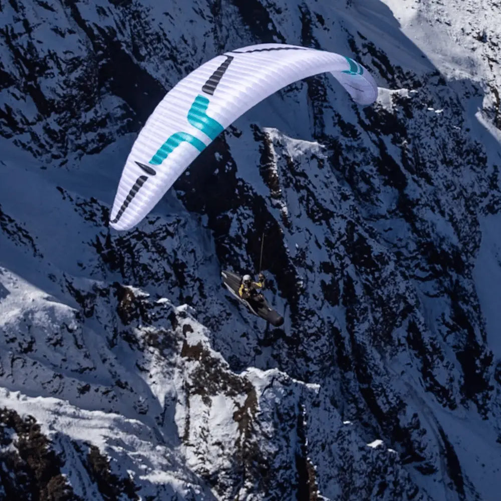 Weisser Ozone Alpina 5 (EN-C) Gleitschirm über Berglandschaft, ideal für erfahrene Gleitschirmpiloten, bekannt für leichtes Gewicht und hohe Leistung.