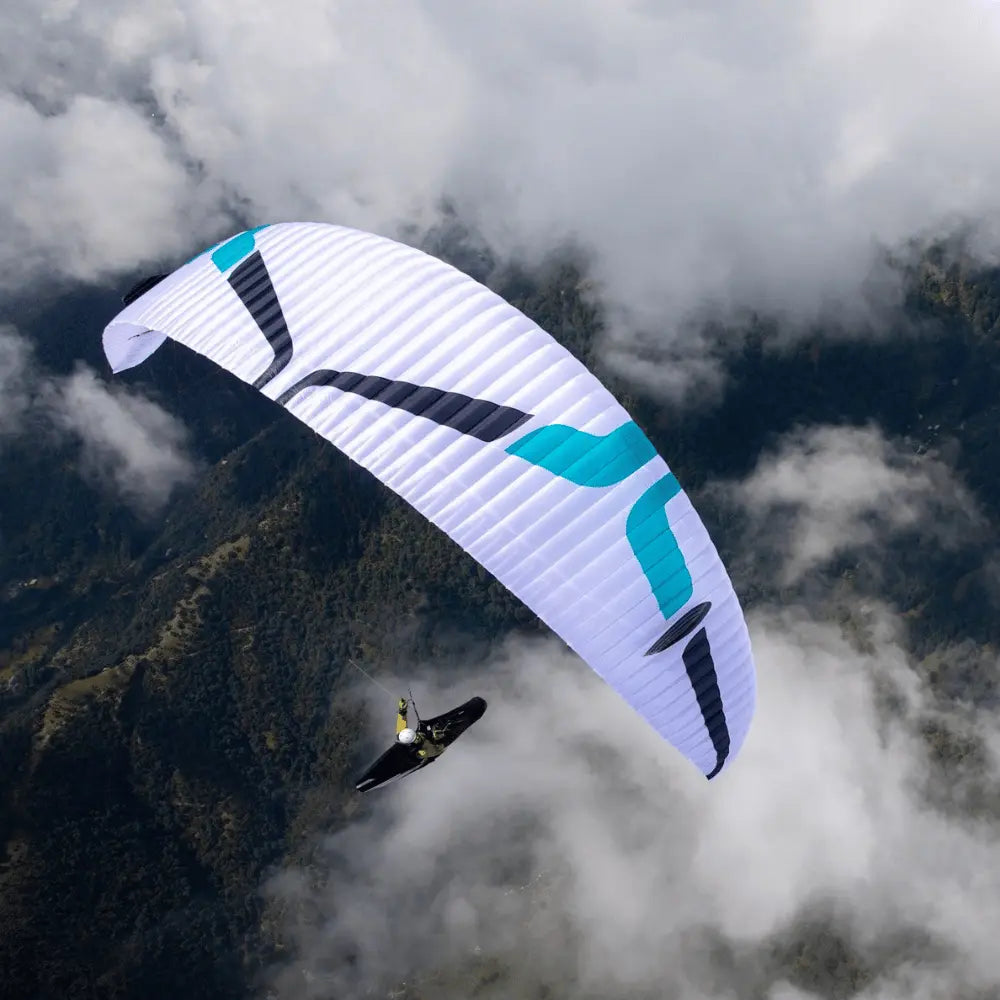 Person gleitet mit Ozone Alpina 5 (EN-C) Paraglider über Berglandschaft, repräsentiert leichtgewichtige Sportleistung und hohe Sicherheit. Perfekt für erfahrene Gleitschirmpiloten.