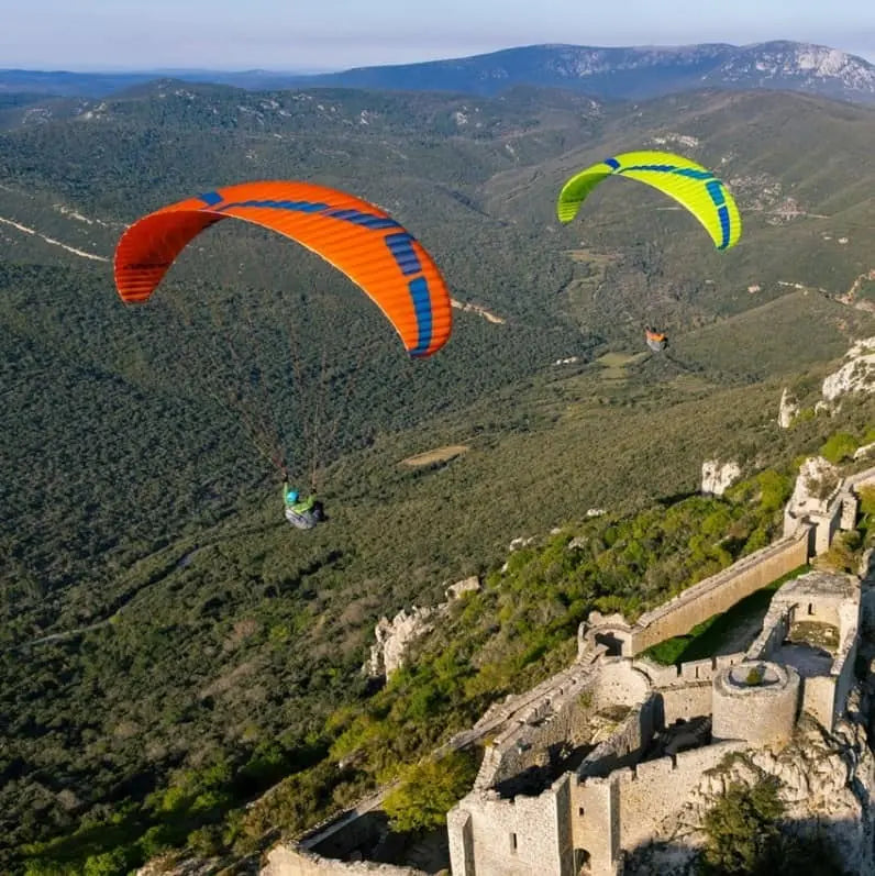 Ozone Buzz Z7 (Mid EN-B) Paraglider über schneebedecktem Berg, ideal für XC-Flüge mit hoher passiver Sicherheit und verbesserter Flugeffizienz, sichtbar in der Luft.