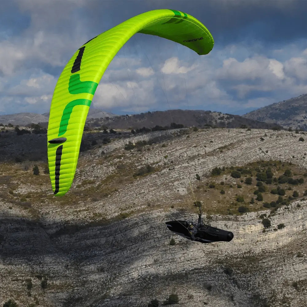 Ozone Delta 5 (EN-C) Gleitschirm in Aktion über Bergen, zeigt exzellente Leistung und Sicherheit beim Paragliding, ideal für fortgeschrittene Piloten.