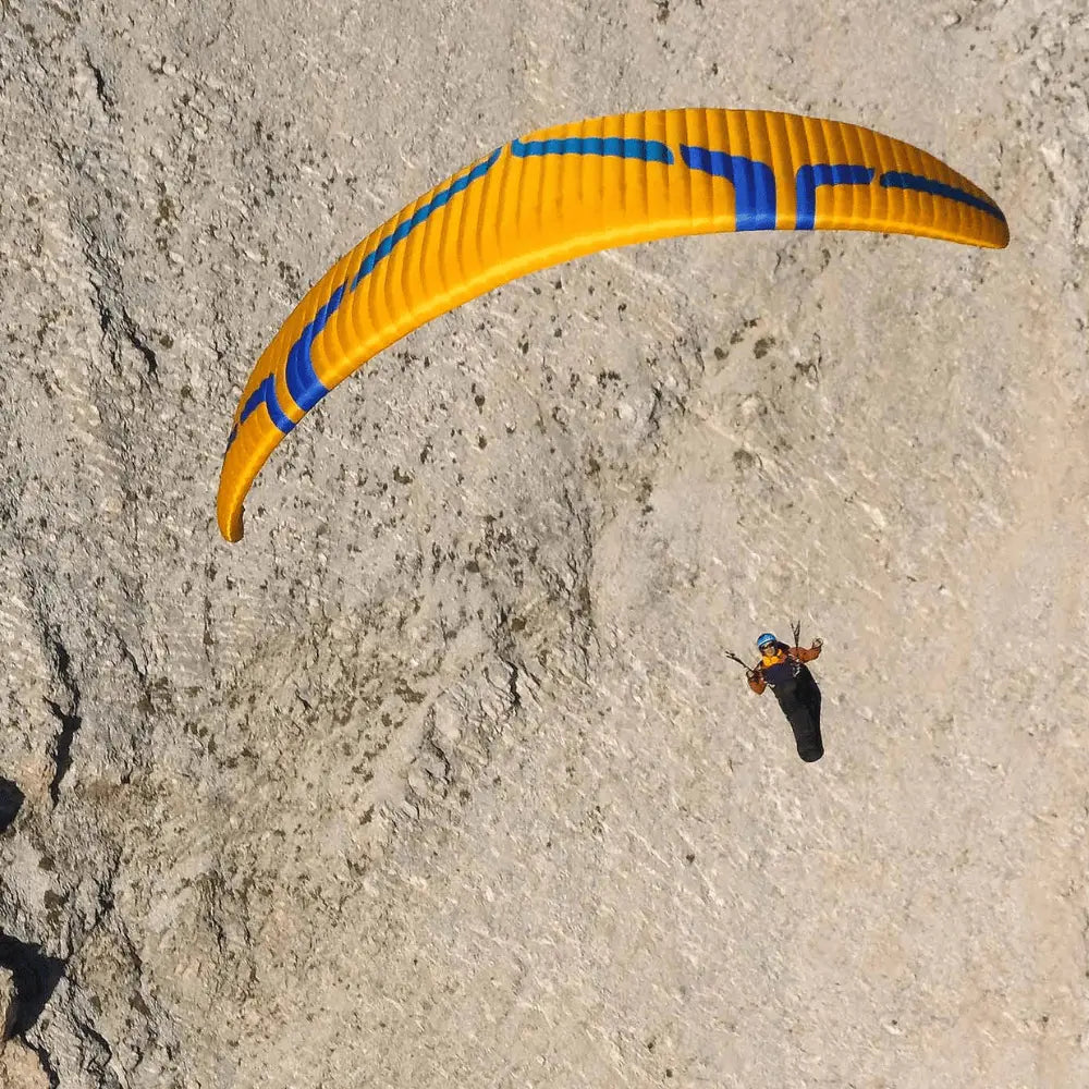 Person fliegt mit Ozone Rush 6 Gleitschirm in der Luft, ideal für erfahrene Piloten, bekannt für hohe Leistung und Stabilität.
