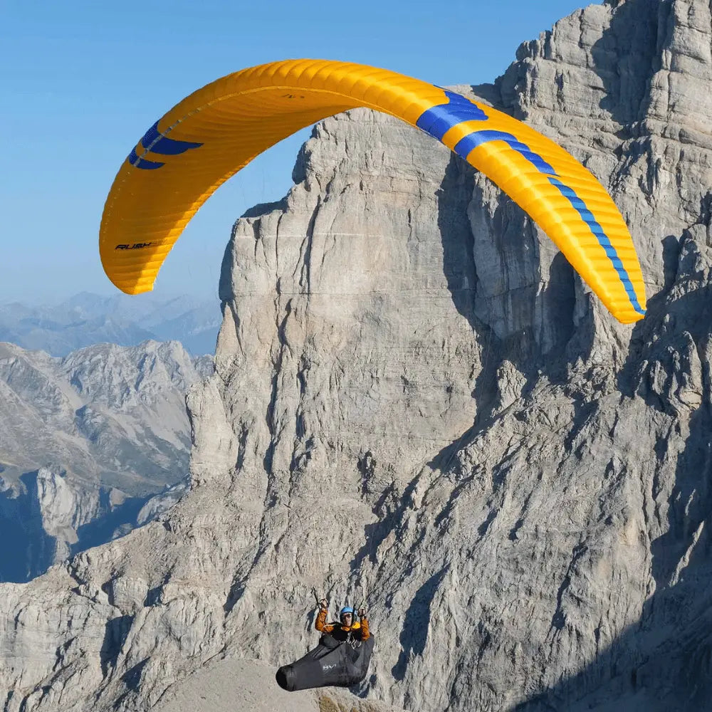 Ozone Rush 6 (High EN-B) im Flug über Berglandschaft, gezeigt bei Paragliding-Aktivität, ideal für anspruchsvolle Gleitschirmflieger.