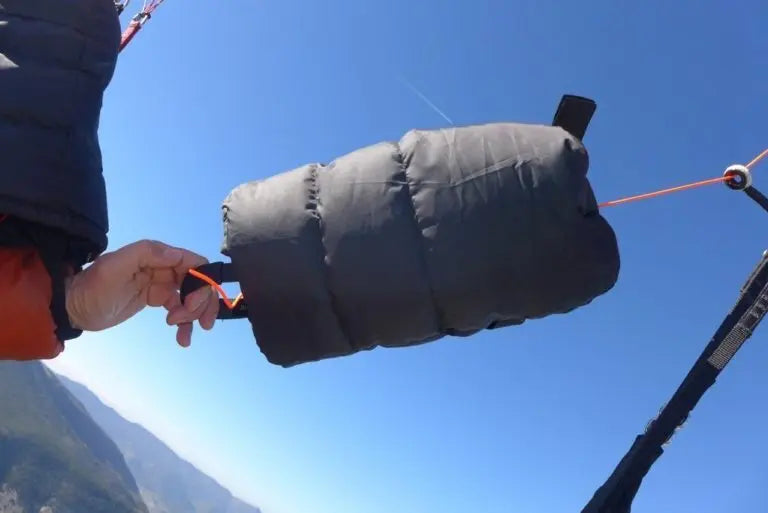 Hand hält WindsRiders Warm Sleeve Muffles K2-ZIP, ideal für Gleitschirmflieger, gefüllt mit echter Daune für exzellente Wärmeisolierung bei Outdoor-Abenteuern.