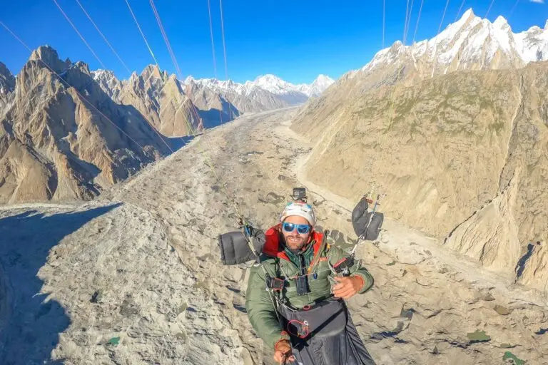 Mann paragleitet über Berg, trägt WindsRiders Warm Sleeve Muffles K2-ZIP, gefüttert mit echter Daune für optimale Wärmeisolierung beim Fliegen.