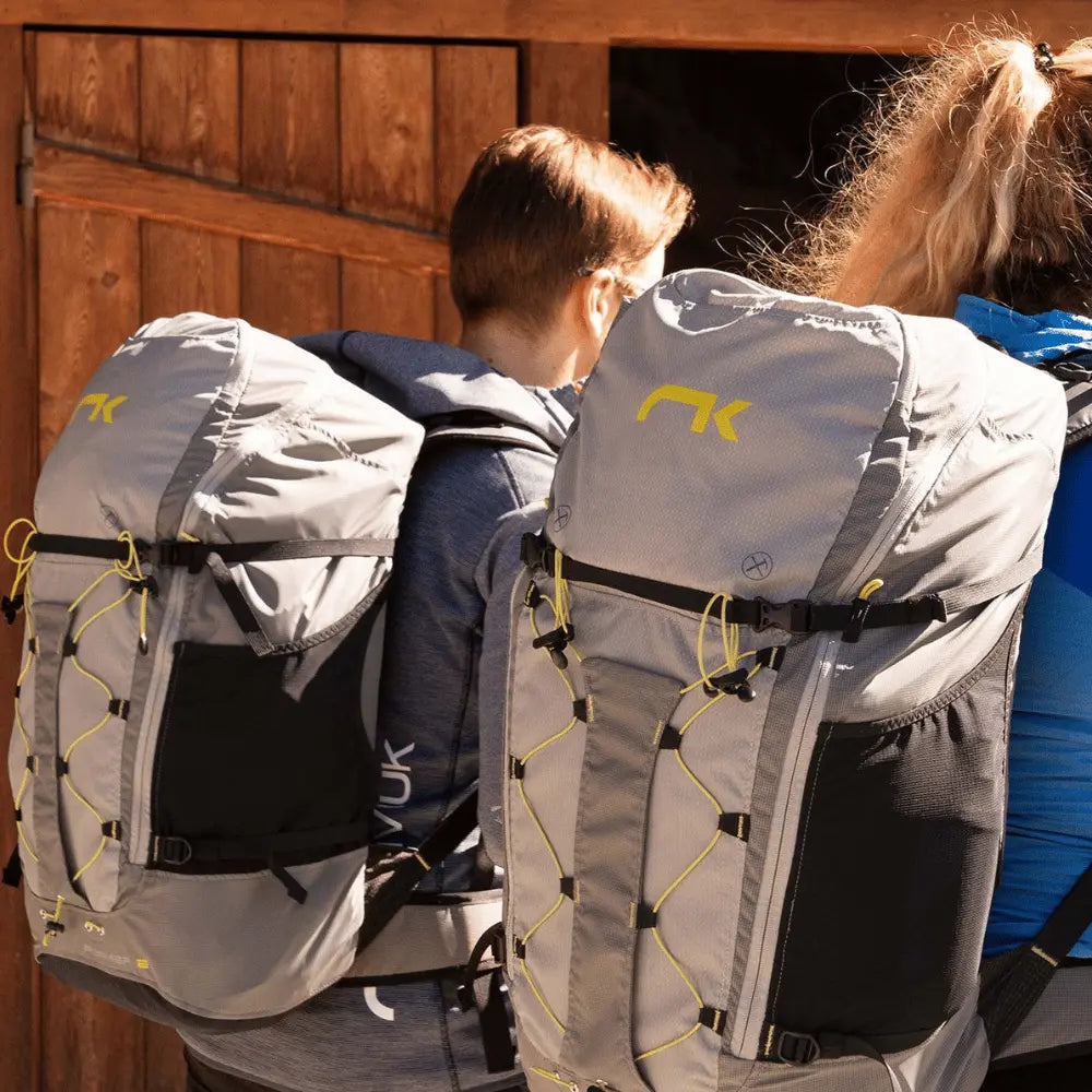 Paar mit Niviuk Roamer 2 Hike&Fly Gurtzeug, das verbesserten Tragekomfort und innovative Lastverteilung für Gleitschirmabenteuer bietet.