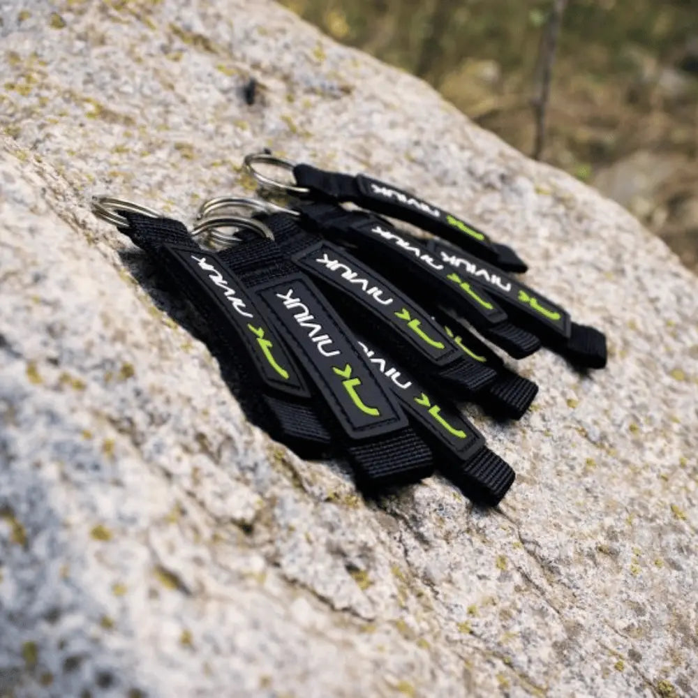 Niviuk Schlüsselanhänger auf hellem Felsen präsentiert; robustes, schwarzes Paragliding-Zubehör mit Metallring, ideal für Schlüsselbund oder Rucksack.