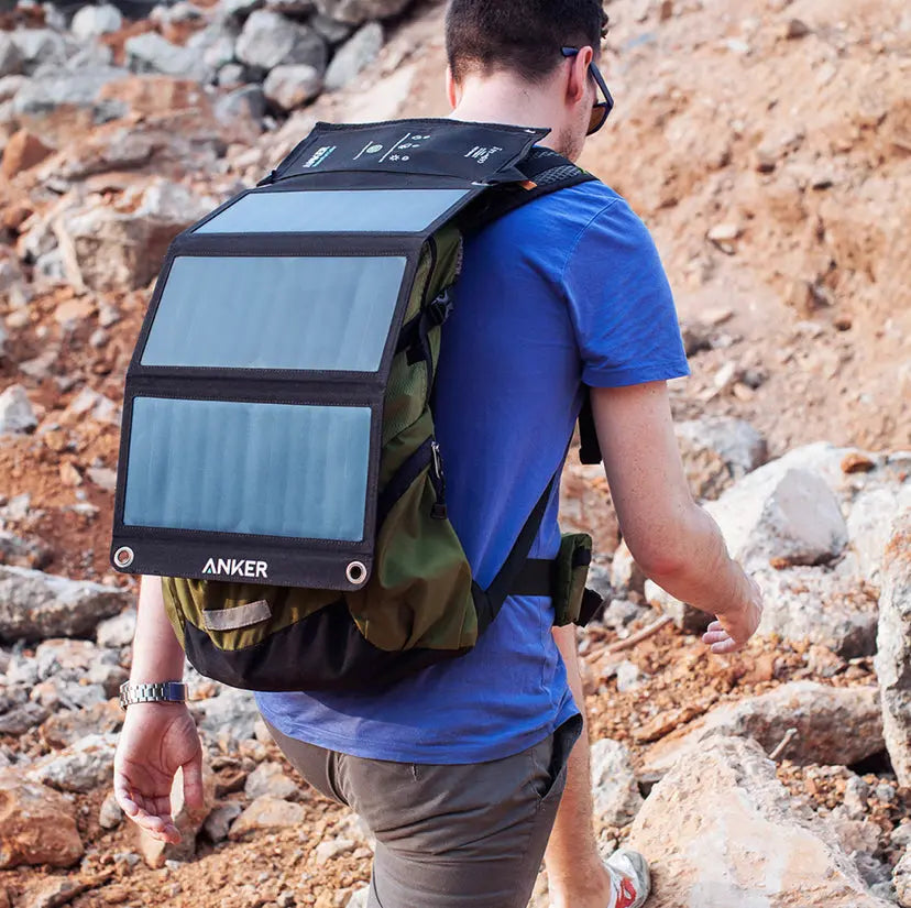 Mann mit Solarpanel PowerPort 21W auf dem Rücken beim Wandern, ideal für Trekkingtouren und autarkes Aufladen unterwegs. Hochwertiges Zubehör für Gleitschirmflieger.