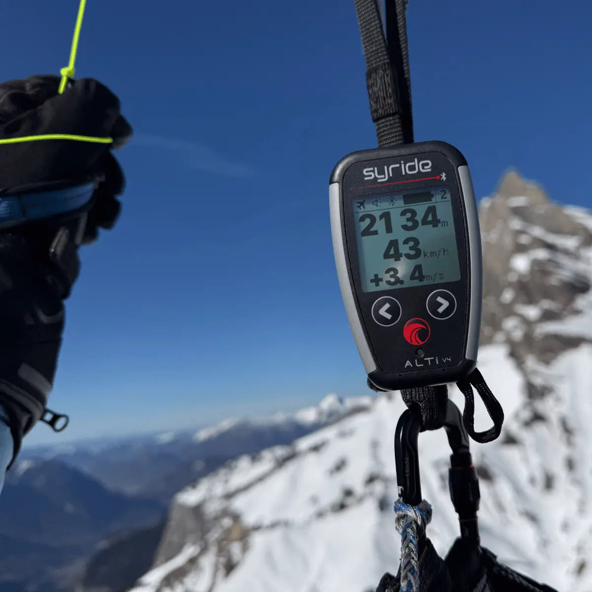 Syride Alti V4, ultraleichtes Vario-Instrument für Gleitschirmflieger, zeigt Höhen-, Geschwindigkeits- und Steigdaten auf seinem Display, befestigt an einem Karabiner.