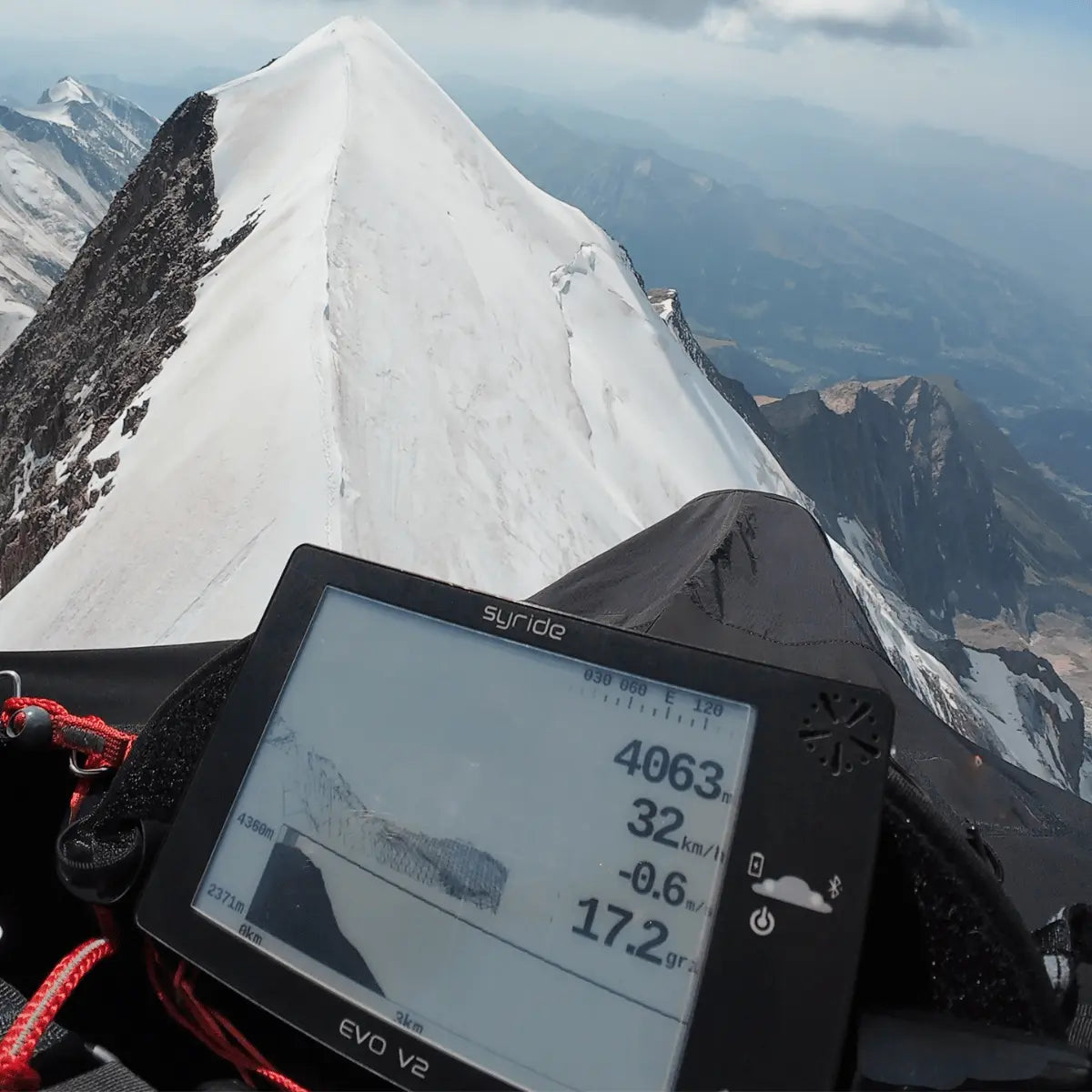 Syride Evo V2 Variometer in Nahaufnahme während eines Gleitschirmflugs über schneebedeckten Berggipfeln, ideal für Paragliding und Hike & Fly Aktivitäten.