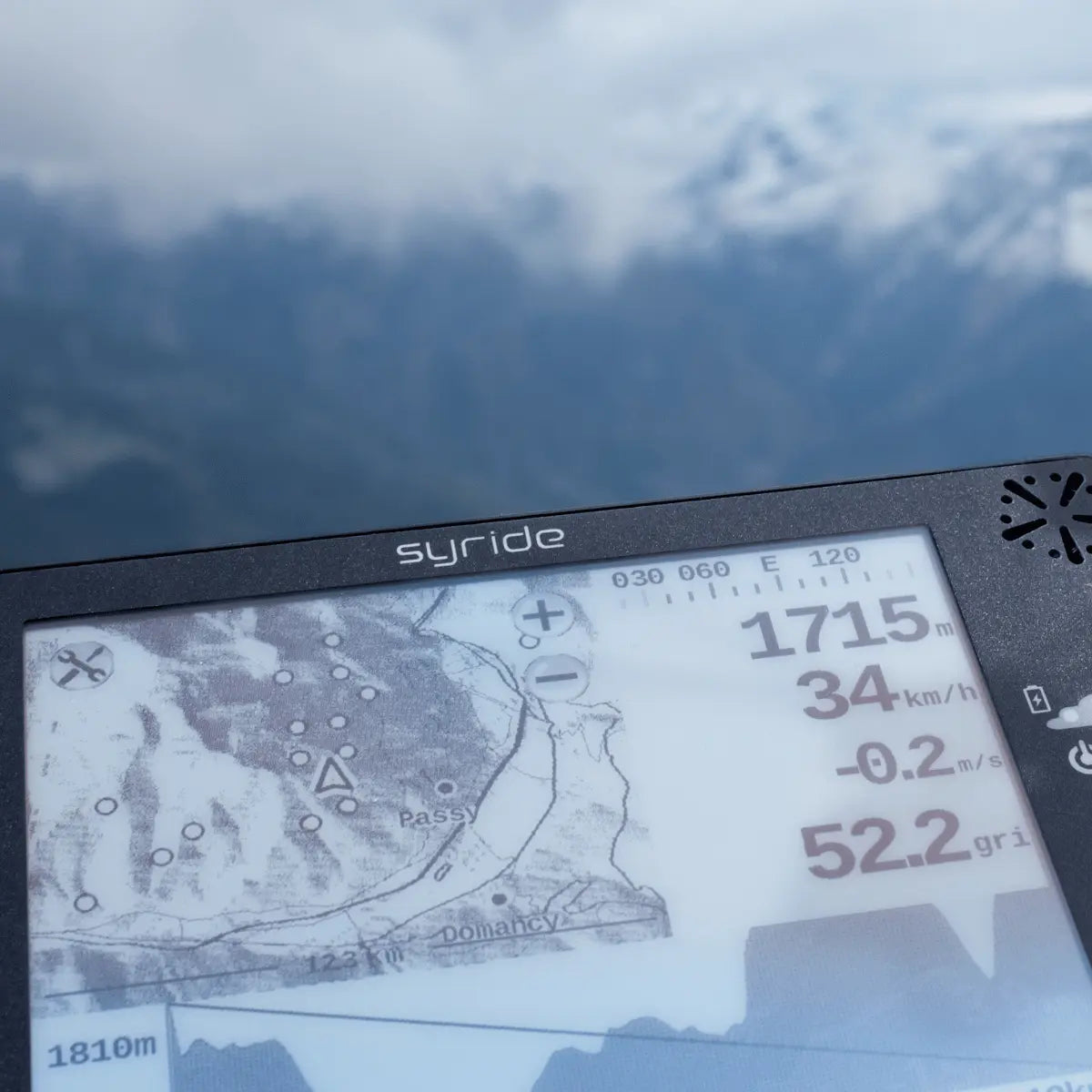 Nahaufnahme des Syride Evo V2 Variometers mit Kartenanzeige und Flugdaten vor Bergkulisse, ideal für Gleitschirmflieger und Hike & Fly Enthusiasten.