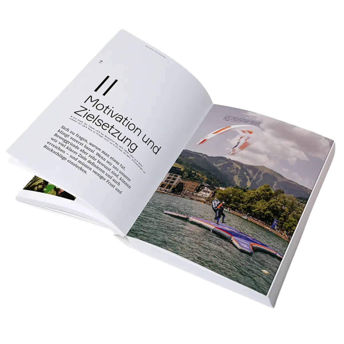 Offenes Buch mit einem Kapitel über Motivation und Zielsetzung neben einem Foto von einem Gleitschirmflieger über einem See vor Bergkulisse, dargestellt in der Wanderbird Strategie von Paul Guschlbauer.