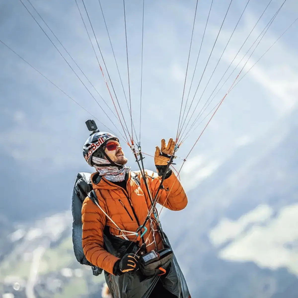 Mann in orangefarbener Jacke mit Helm und Handschuhen bereitet sich auf Gleitschirmflug vor, passend zur Wanderbird Strategie von Paul Guschlbauer.