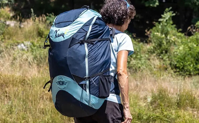 Frau trägt Icaro Xema 2 Wendegurtzeug mit optimiertem Tragekomfort und Airbag-Schutz, ideal für Hike & Fly Touren, im Freien.