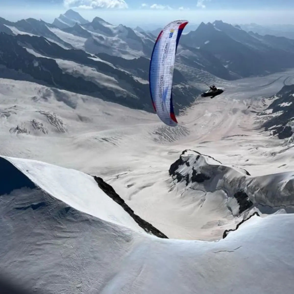 Paraglider mit Pilot fliegt über verschneite Alpenlandschaft, inspiriert von "XPeaks - Neue Wege auf alte Berge!