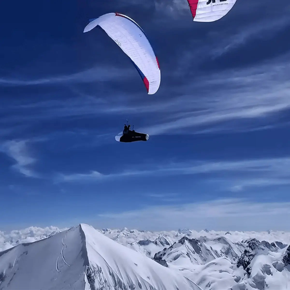 Paraglider mit Pilot Chrigel Maurer fliegt über verschneite Alpenlandschaft, inspiriert von "XPeaks - Neue Wege auf alte Berge!