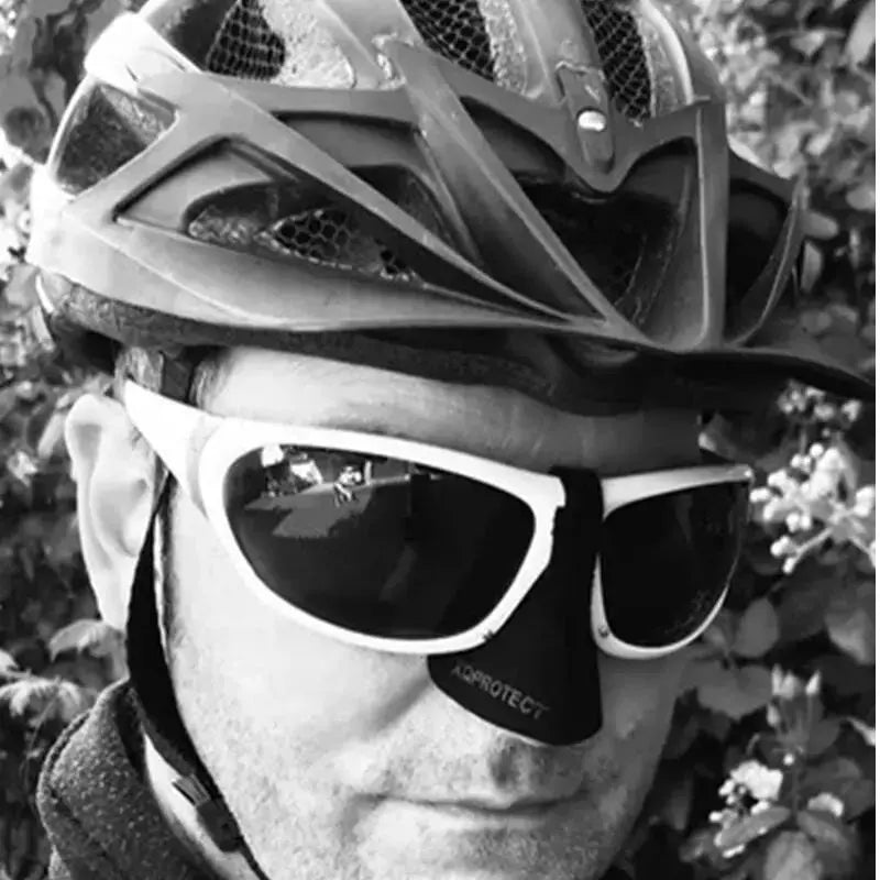 Mann mit Helm und Sonnenbrille trägt Nasen Sonnen- und Kälteschutz für Brillen, ideal für Paragliding und Outdoor-Aktivitäten, schützt effektiv vor Sonne und Kälte.